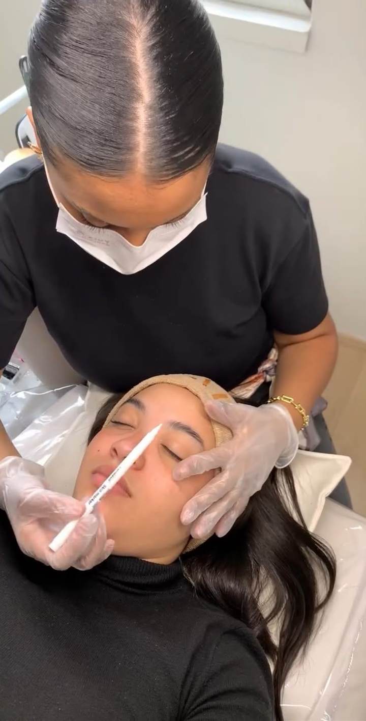 Profissional realizando marcação de visagismo nas sobrancelhas de uma cliente
